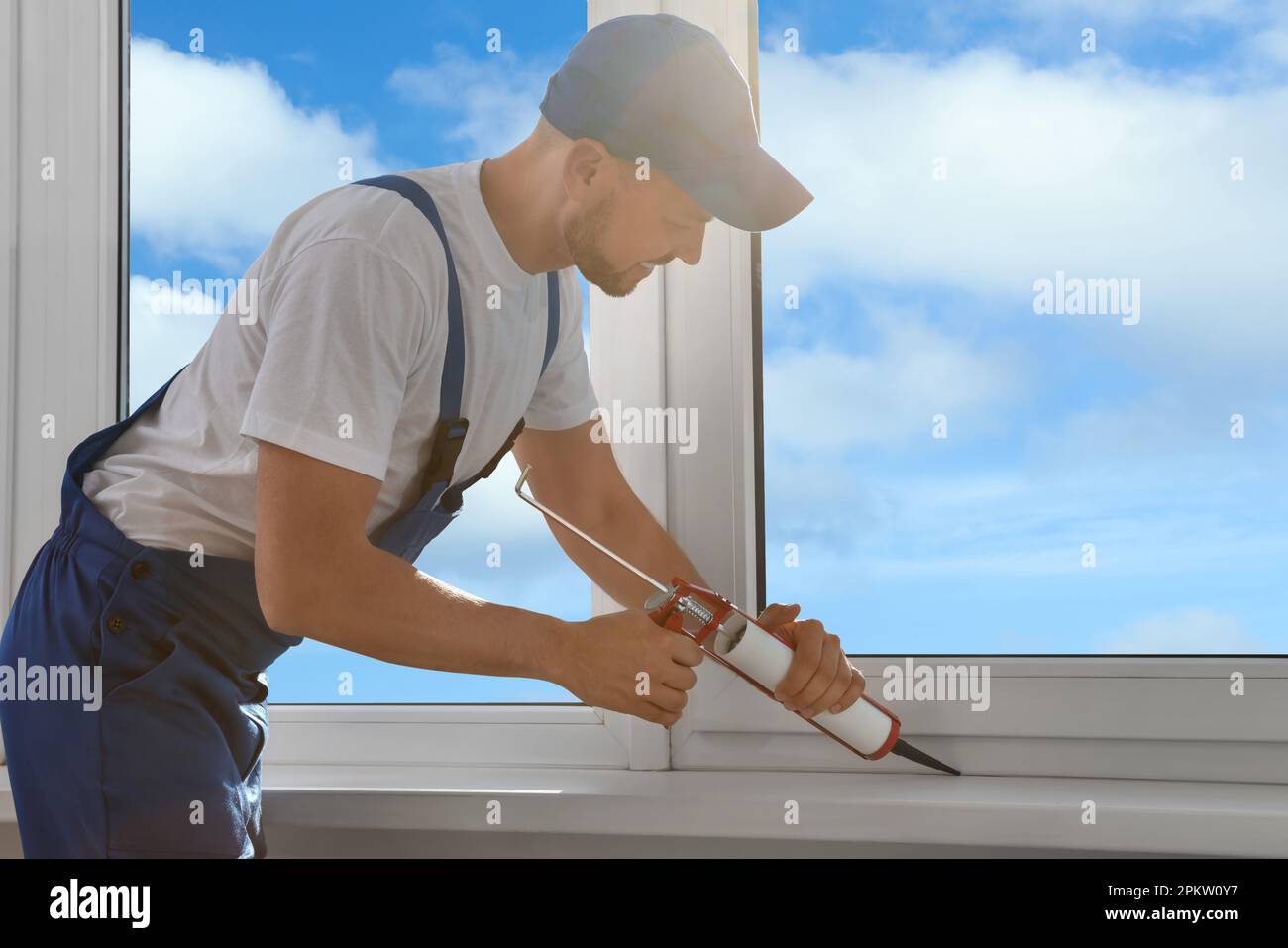 Worker sealing plastic window with caulk indoors. Installation process Stock Photo Alamy