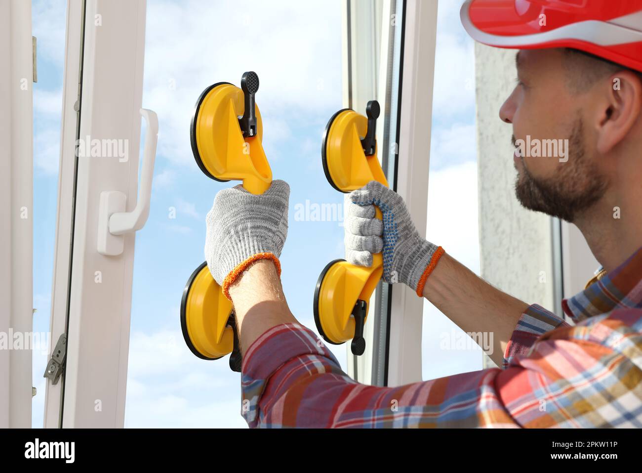 Worker using suction lifters during plastic window installation indoors Stock Photo