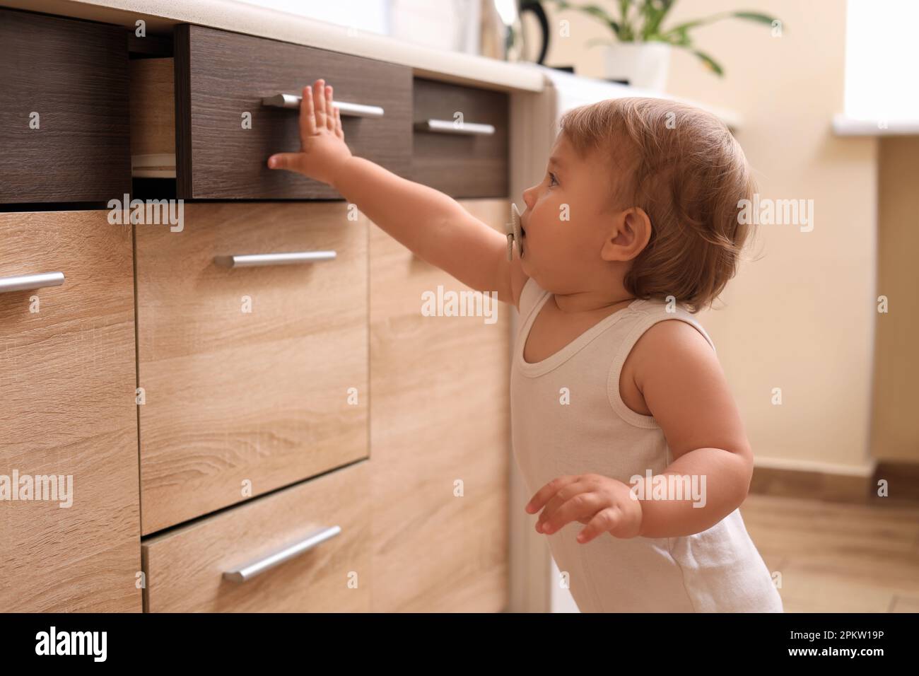 Little child exploring drawer indoors. Dangerous situation Stock Photo