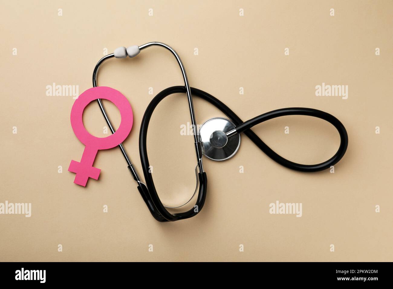 Female gender sign and stethoscope on beige background, flat lay. Women's health concept Stock Photo