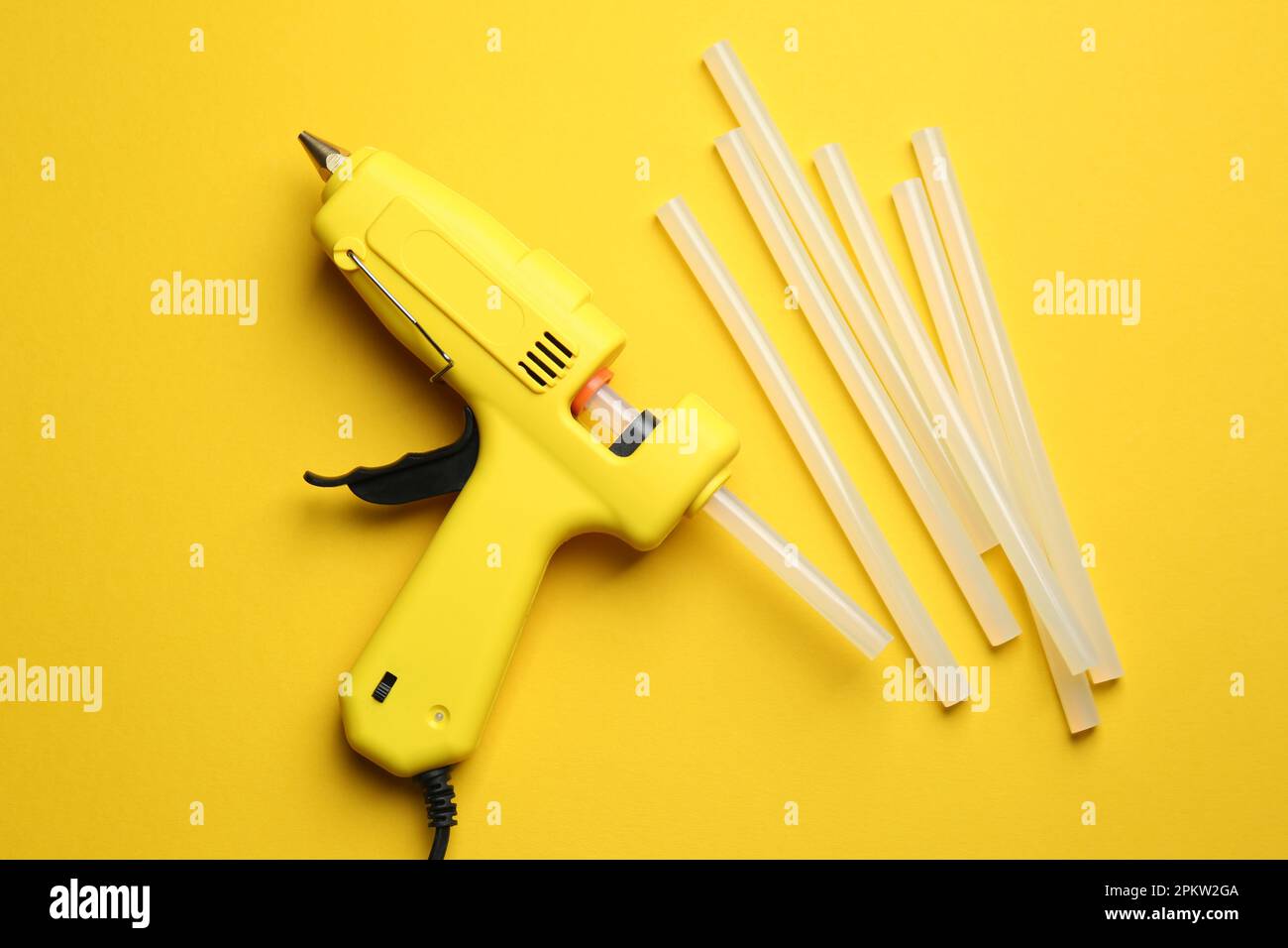 Glue gun and sticks on yellow background, flat lay Stock Photo Alamy