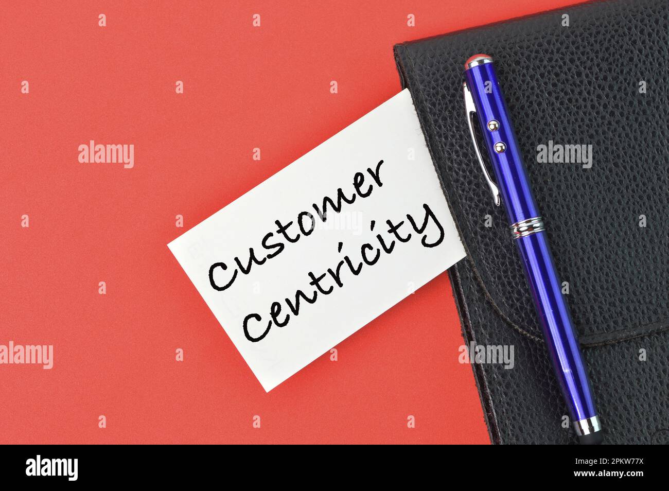 Pen, black file and memo note written with text CUSTOMER CENTRICITY. Stock Photo