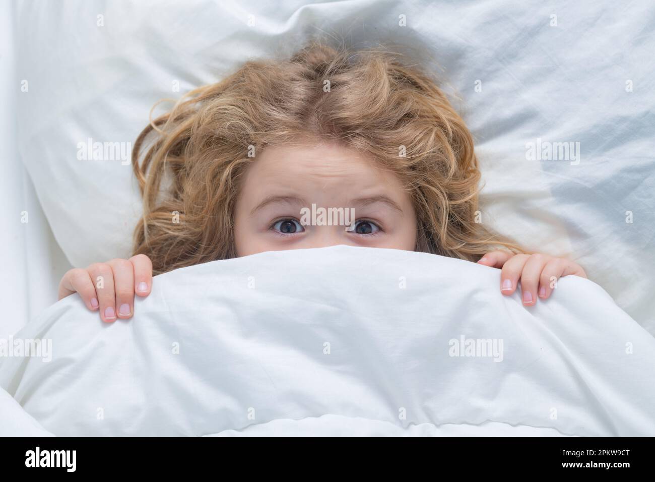 Nightmare kids, child hiding under white blanket, top view. Scared boy