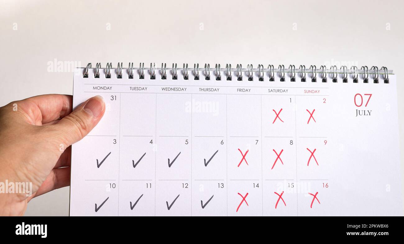 Desk calendar with ticks and crosses, depicting four day work week concept. Stock Photo
