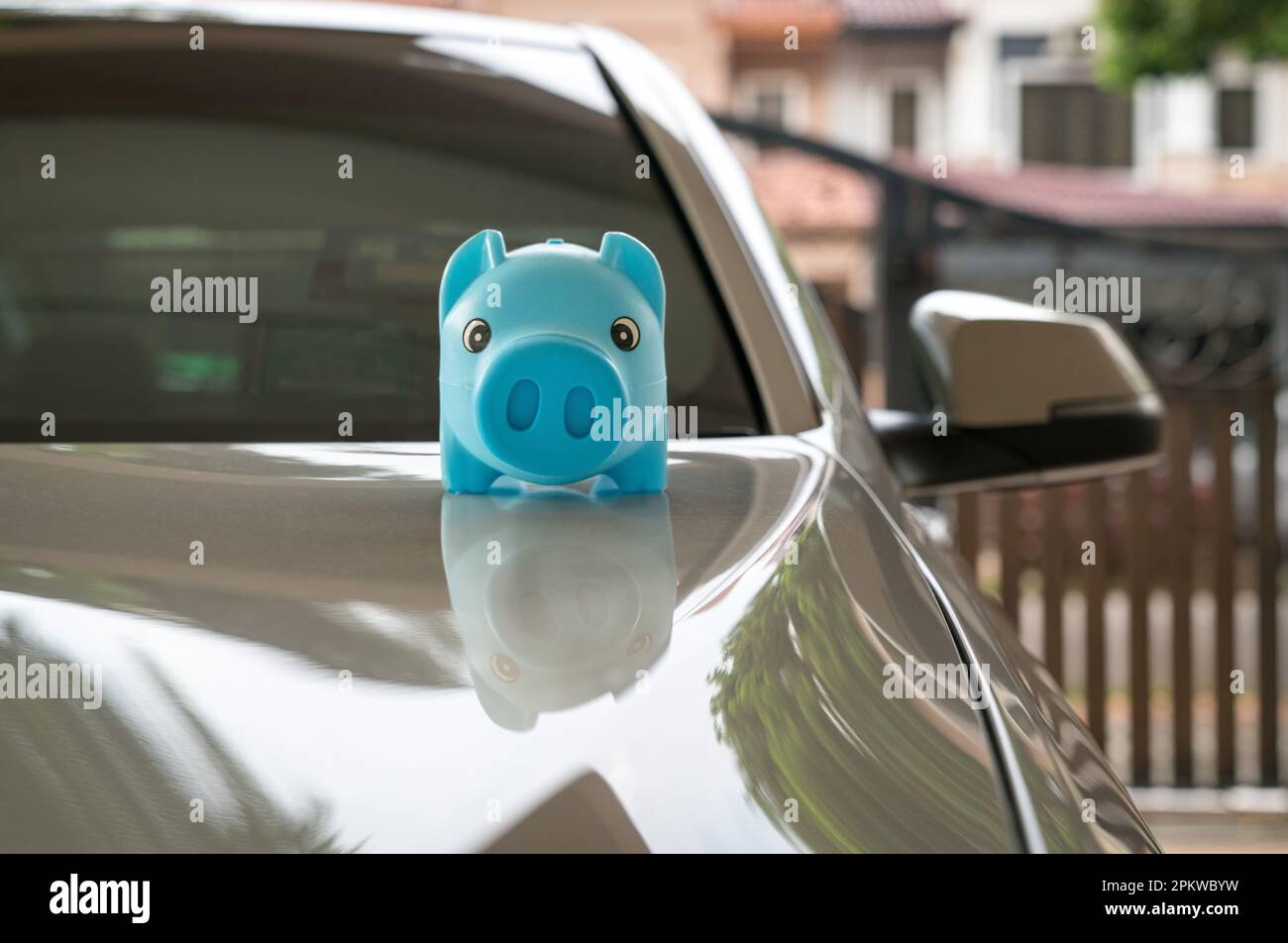 Blue piggy bank money box on top of white car. Car purchase and insurance concept. Stock Photo