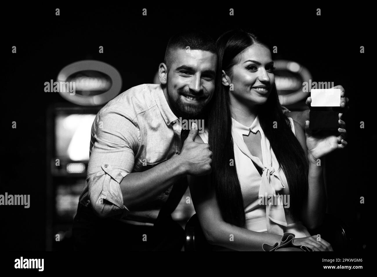 Portrait of a Young Beautiful and Well Dressed Couple Playing in the Casino and Celebrate Holding Vip Card and Man Showing Thumbs Up Stock Photo
