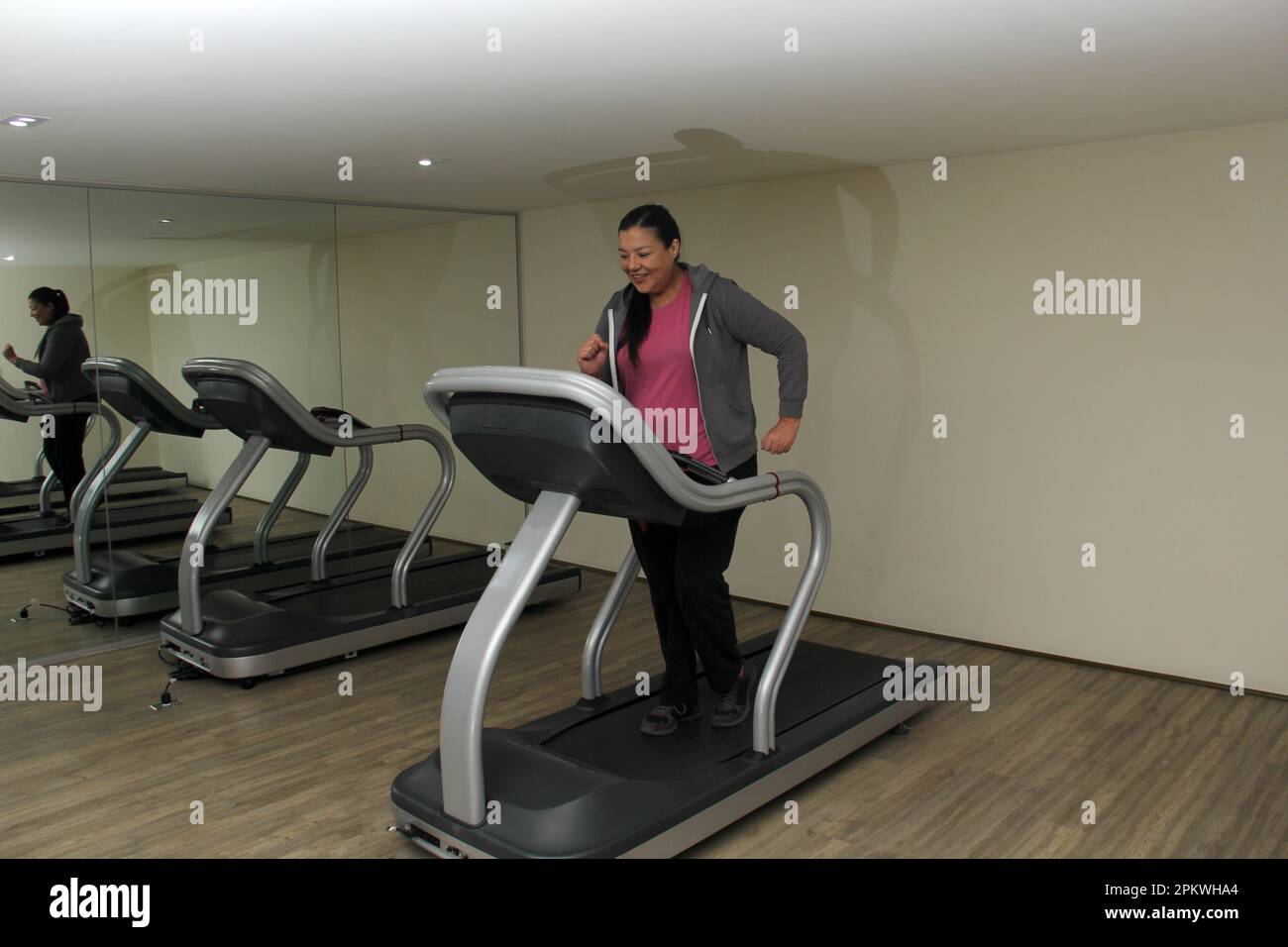 Latino adult woman exercises on treadmill in gym to relax and avoid