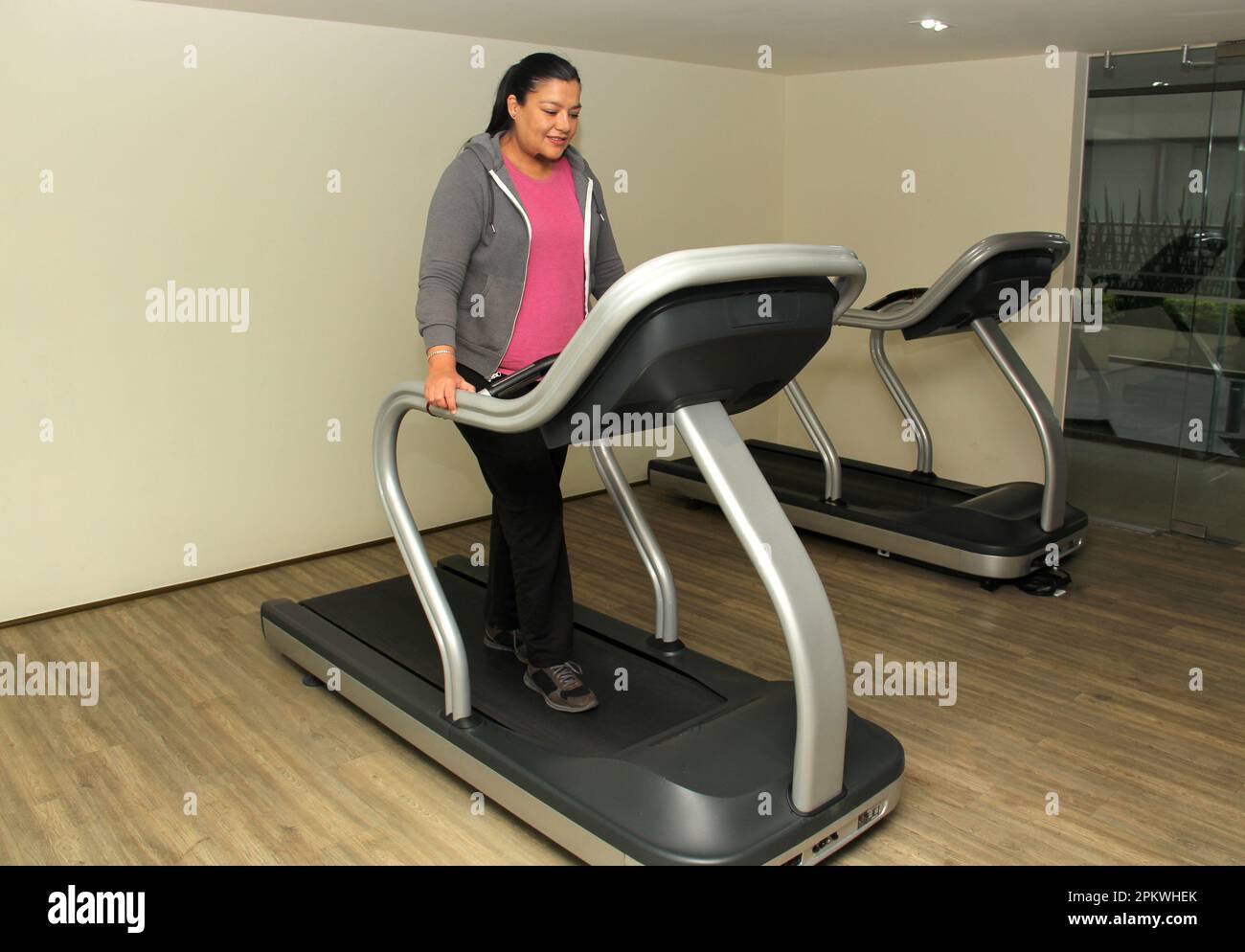 Latino adult woman exercises on treadmill in gym to relax and avoid