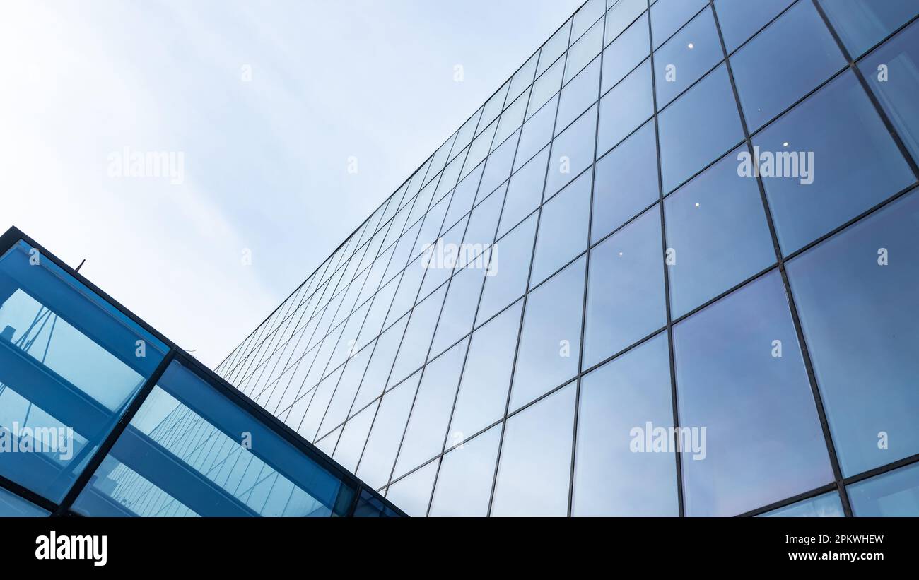 The blue sky is reflected in the windows of a modern office building ...