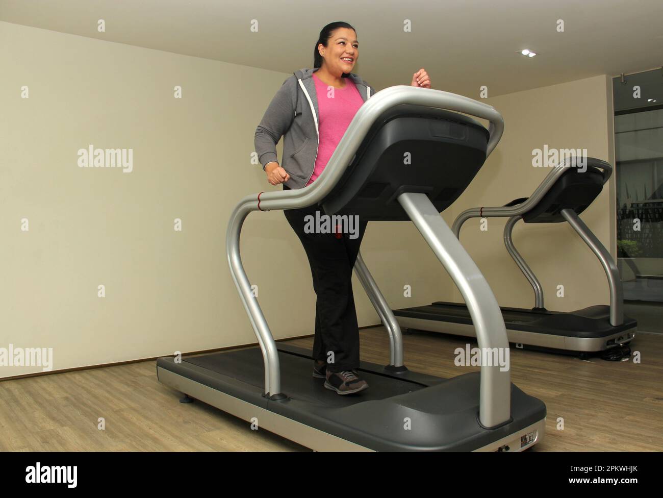 Latino adult woman exercises on treadmill in gym to relax and avoid