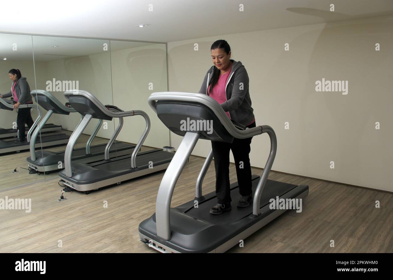 Latino adult woman exercises on treadmill in gym to relax and avoid