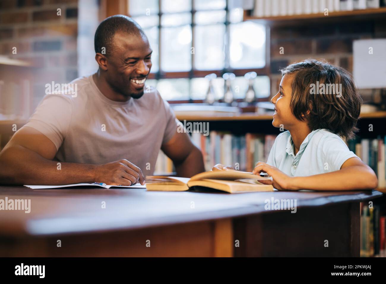 Male elementary school teacher assisting a young boy with school work. Man tutoring a primary school student in a private lesson. Teacher and student Stock Photo