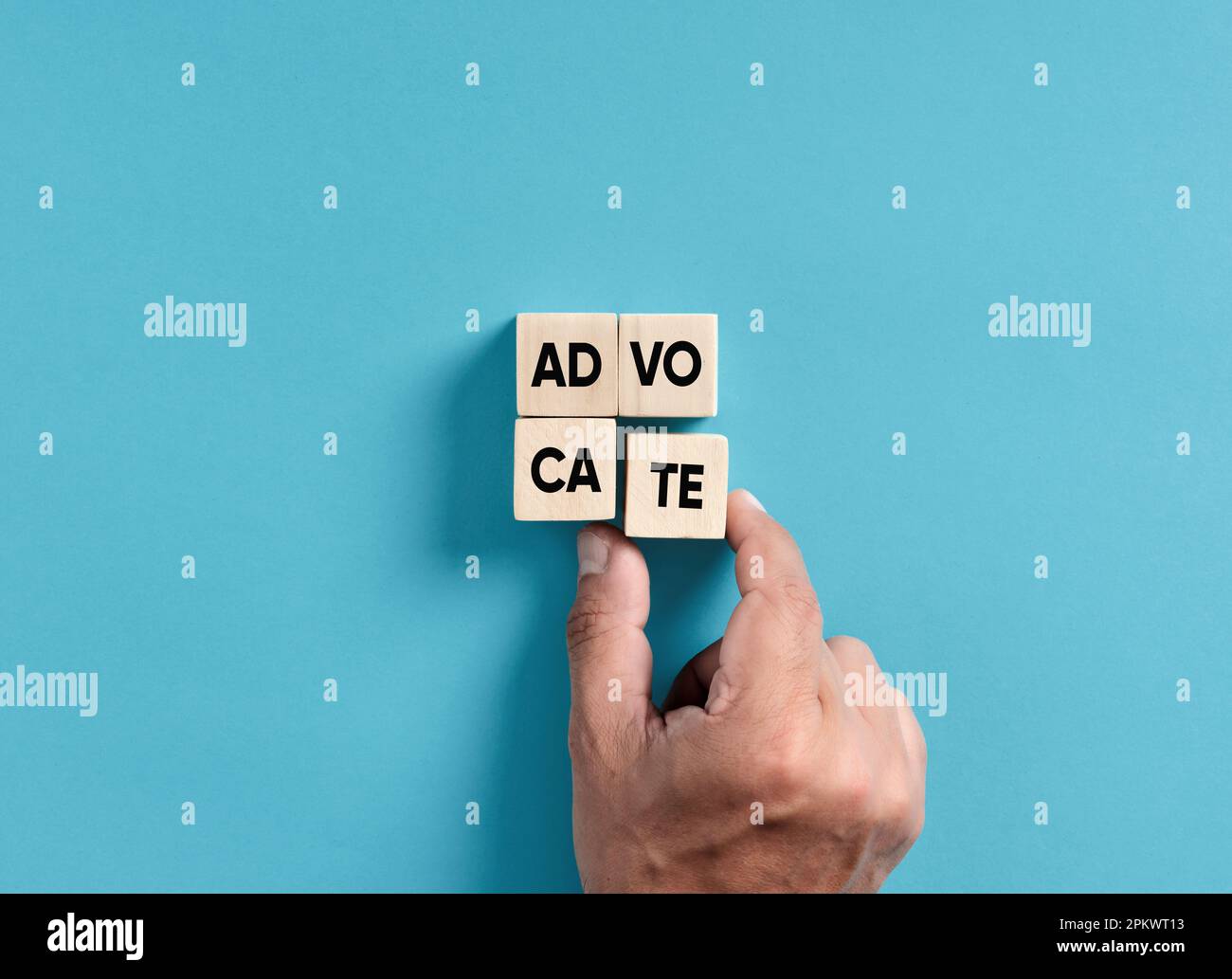 Male hand placing wooden blocks into a square shape to assemble the word advocate. Stock Photo