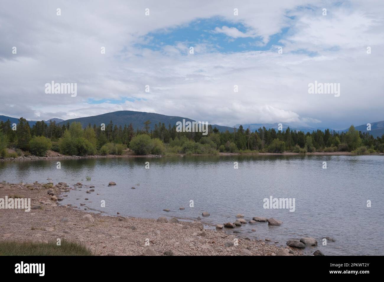 A tranquil lake surrounded by lush trees and majestic mountain peaks in ...