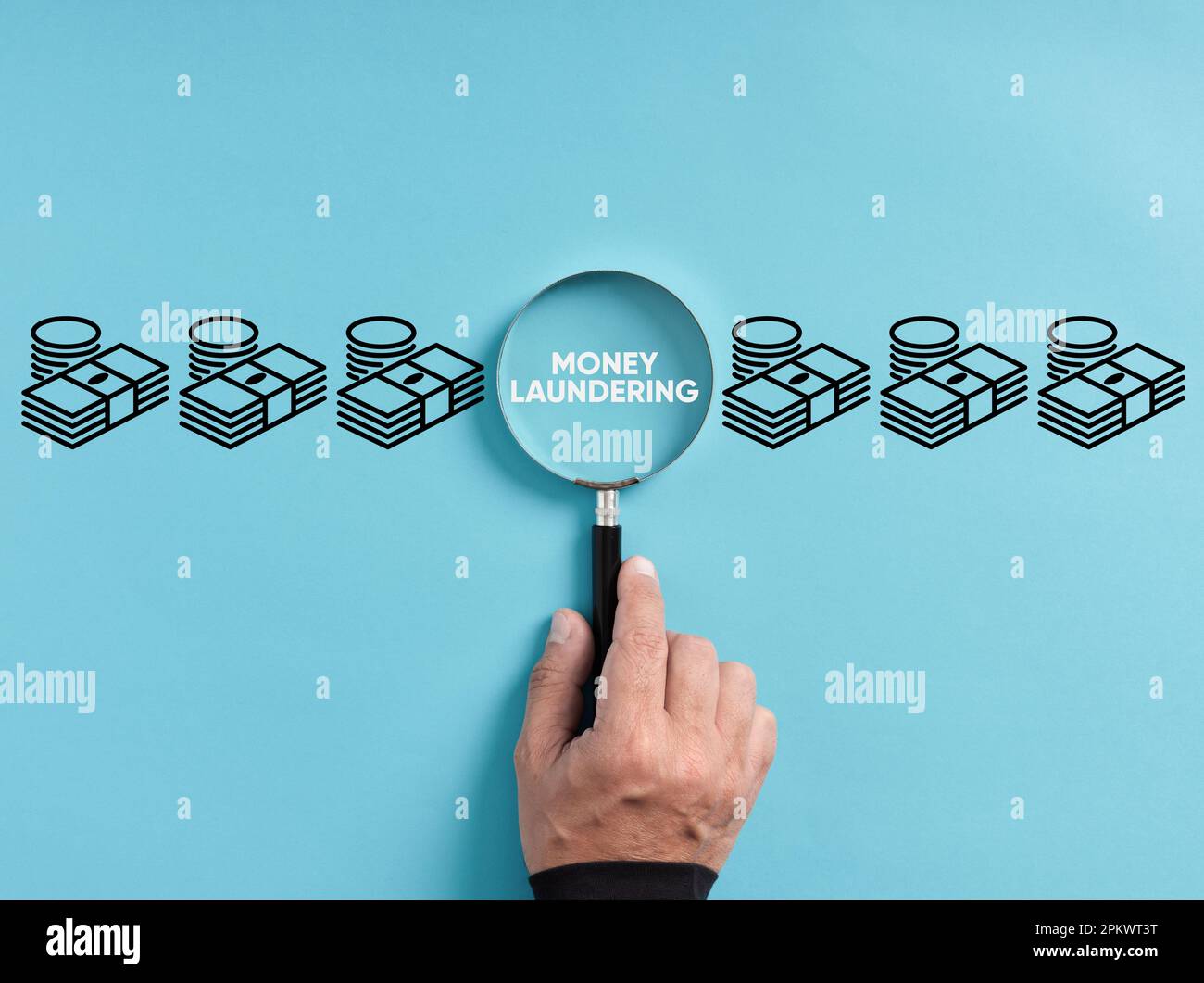 Finding or discovering money laundering crime or fraud. Hand holds magnifying glass focusing on the word money laundering next to money symbols. Stock Photo