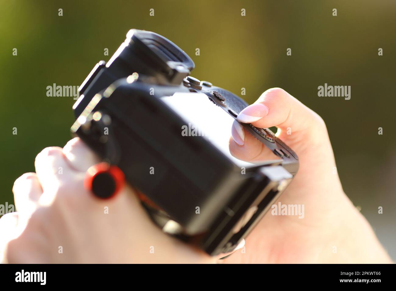 Close up of a photographer hand setting mirrorless camera in a park Stock Photo