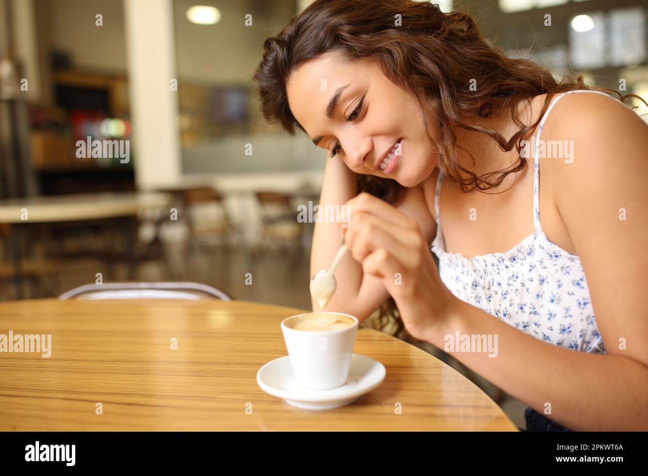 Candid woman stirring coffee sitting in a restaurant Stock Photo