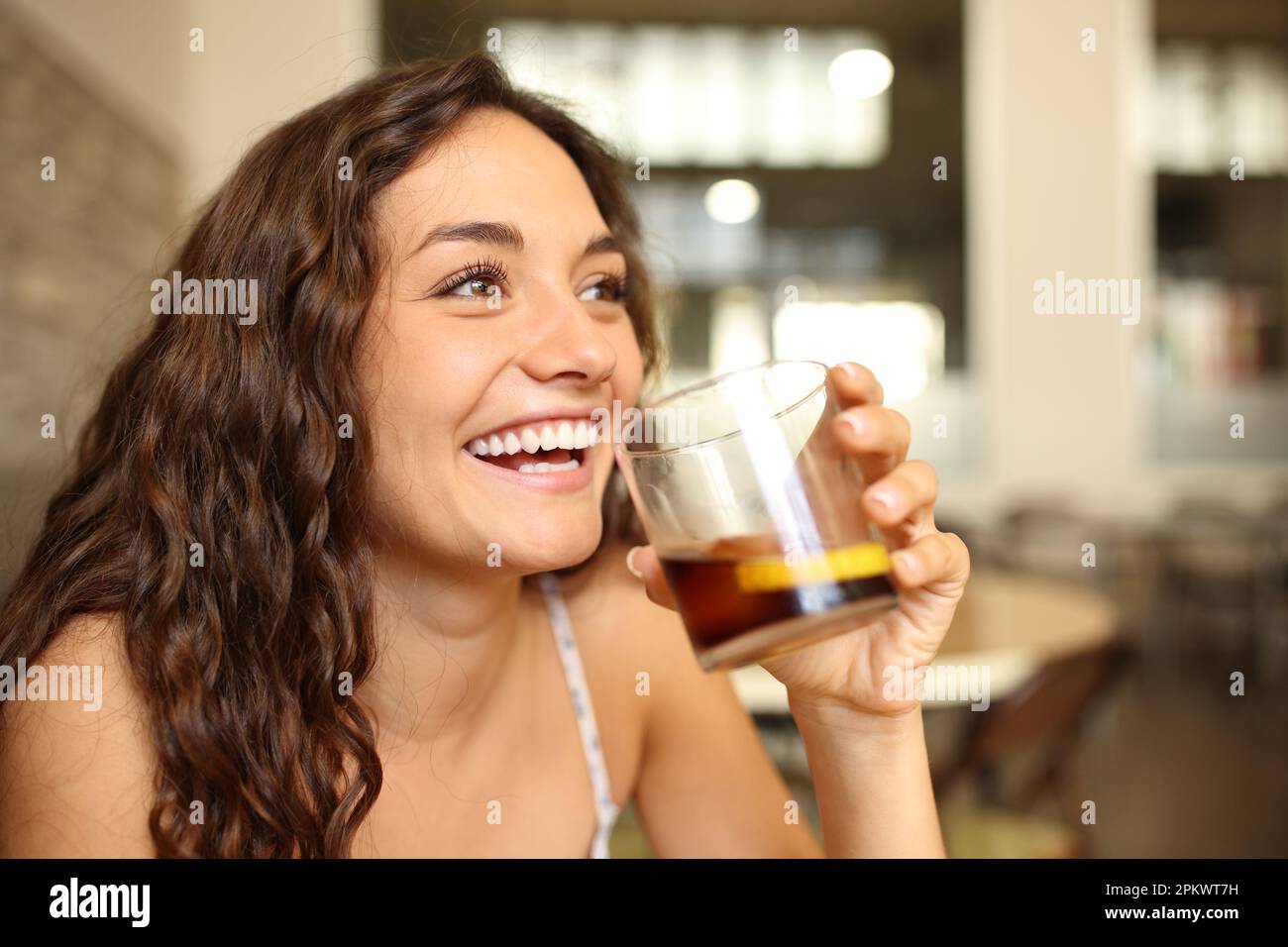 Funny woman laughing holding soda glass in a bar Stock Photo