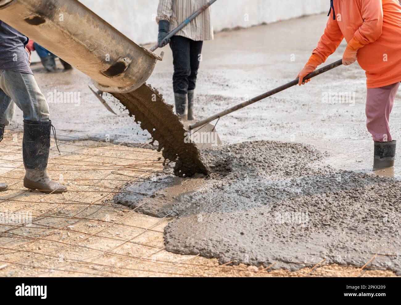 Workers pour the concrete for the construction of a road using mobile concrete mixers. Stock Photo