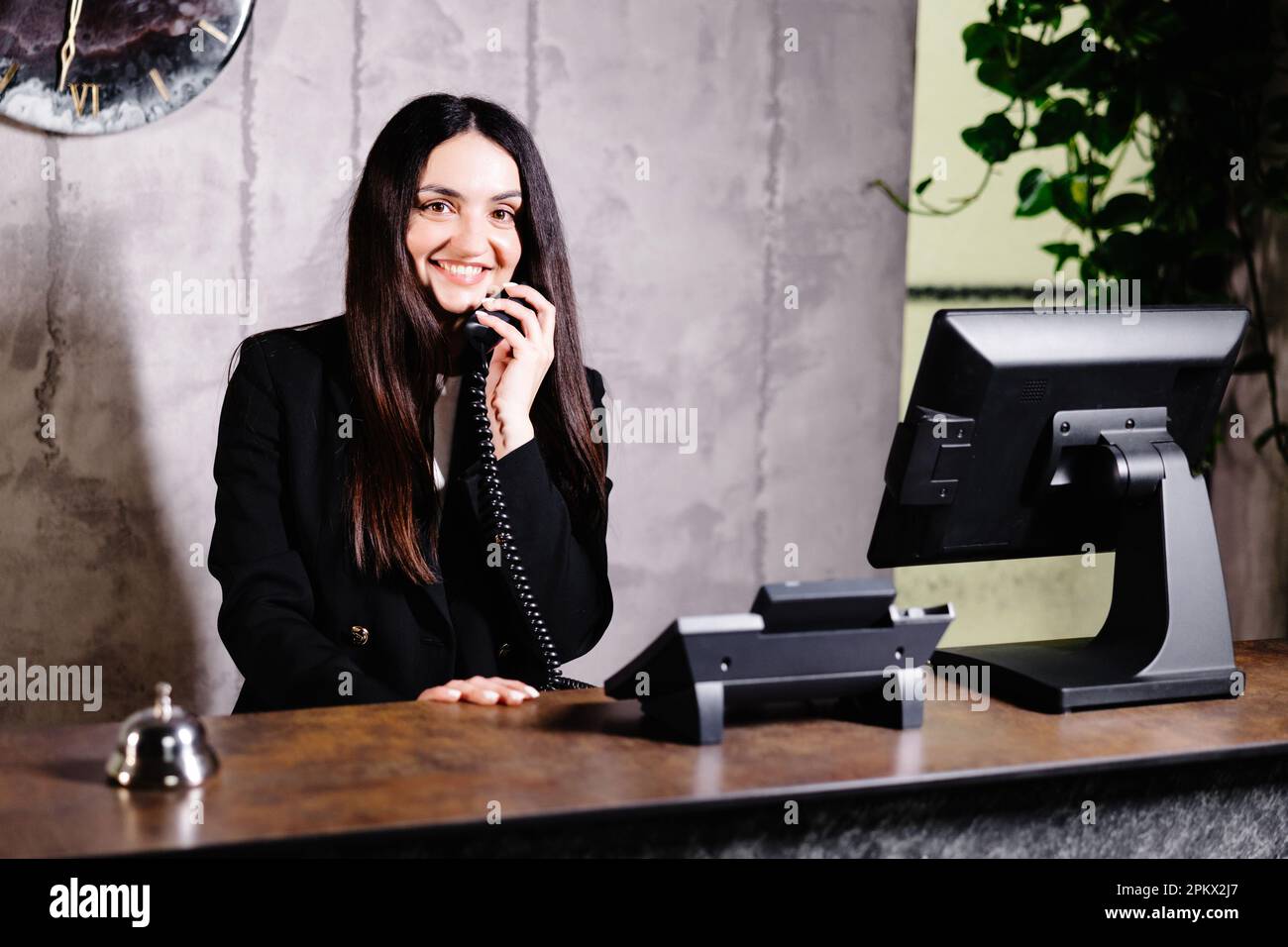 Hotel receptionist. Modern hotel reception desk with bell. Happy female