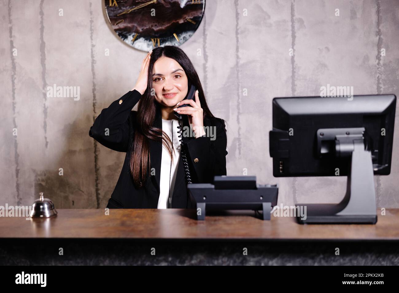 Hotel receptionist. Modern hotel reception desk with bell. Happy female