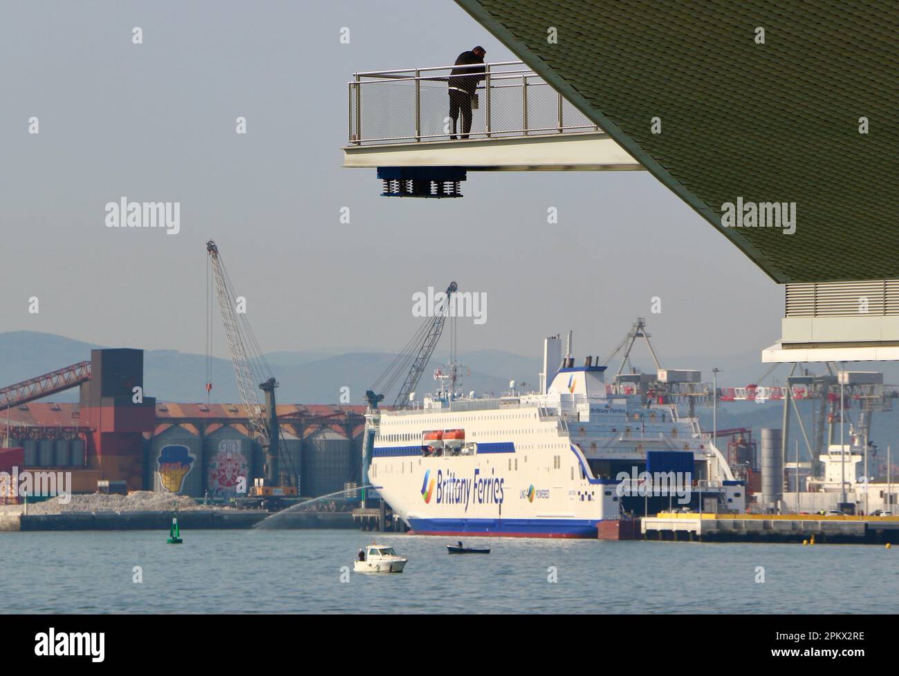 Early spring morning with a man on a walkway at the Centro Botin Botin Centre Arts Centre and a Brittany Ferries ship Santander Cantabria Spain Stock Photo