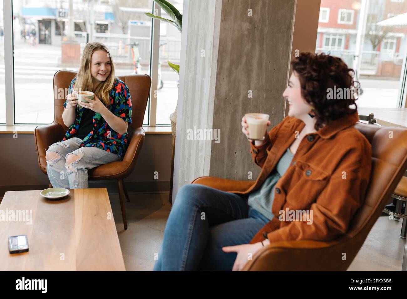 Two young women laughing together in coffee shop Stock Photo