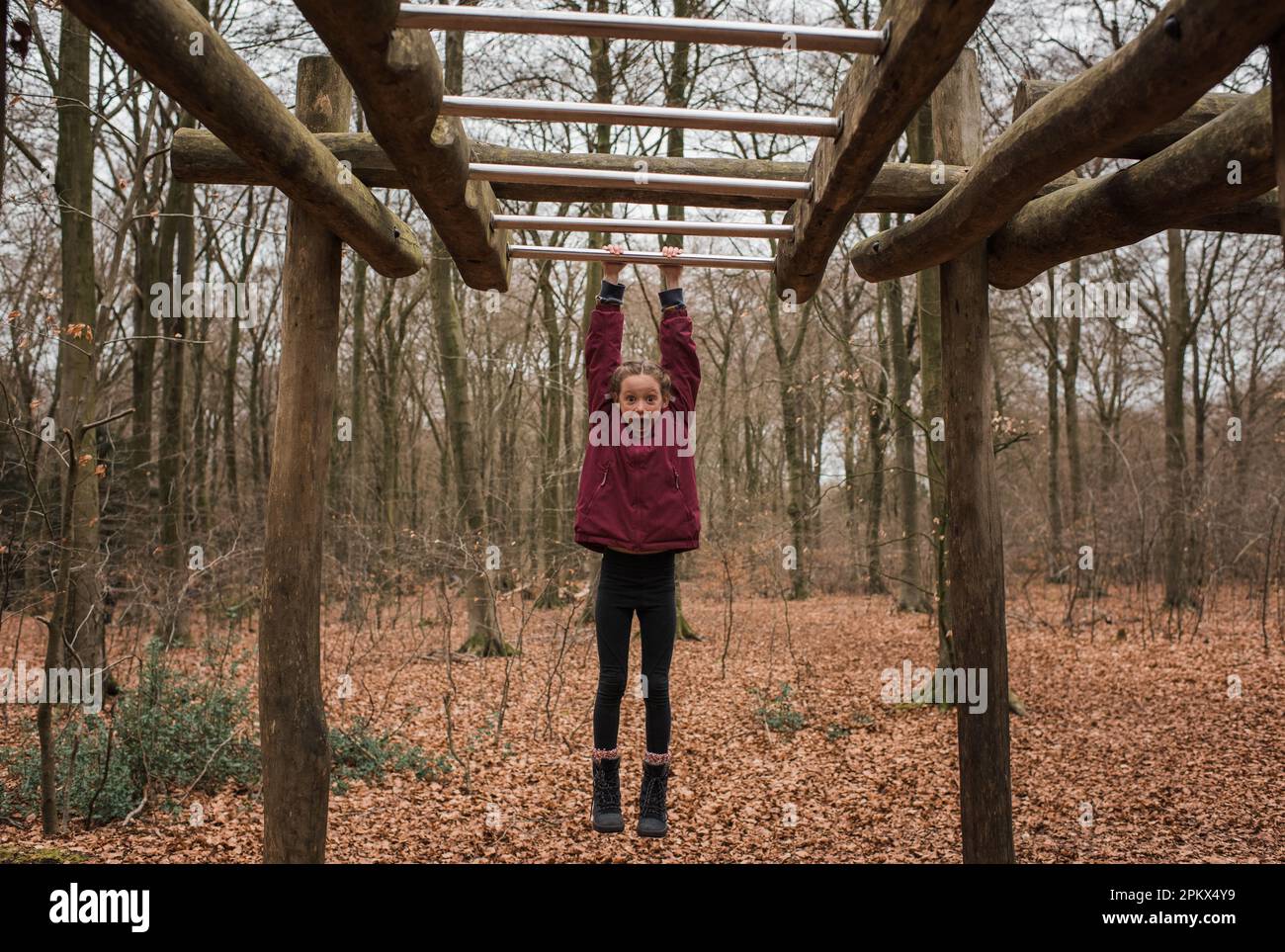 Girl hanging on monkey bars in the forest Stock Photo