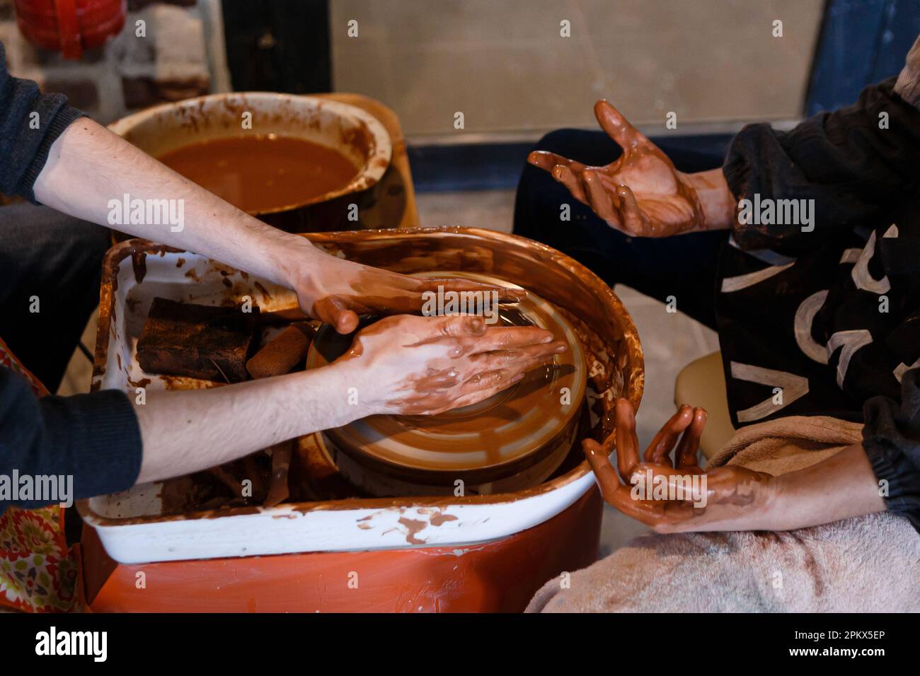 potter with a student on the potter's wheel makes dishes from clay Stock Photo
