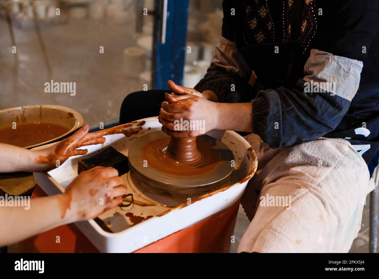 potter with student on potter's wheel makes dishes from clay Stock Photo