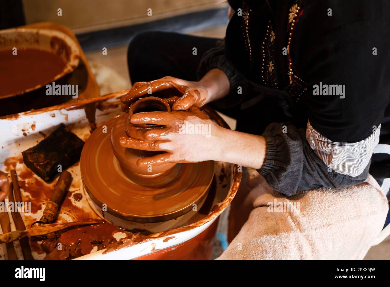 potter with a student on the potter's wheel makes dishes from clay