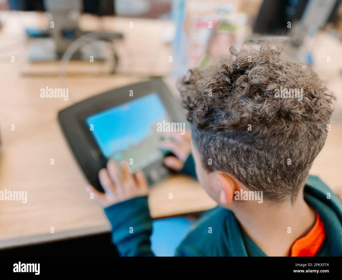 over the shoulder view of mixed race first grader on tablet Stock Photo