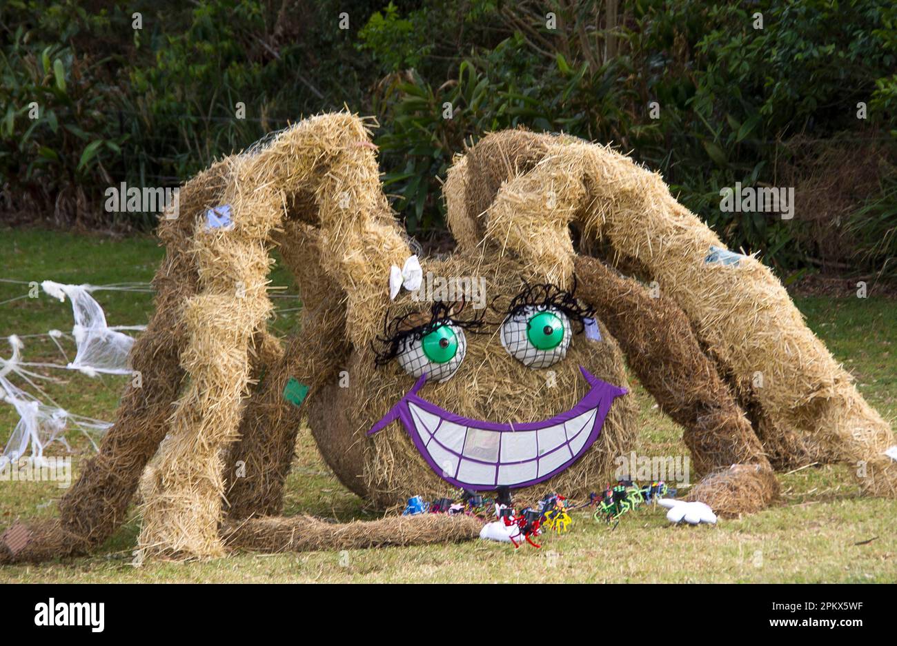 Huge grinning scarecrow in form of a spider made from hay bales. Tamborine Mountain Scarecrow Festival, 2013, Queensland, Australia. Big green eyes. Stock Photo