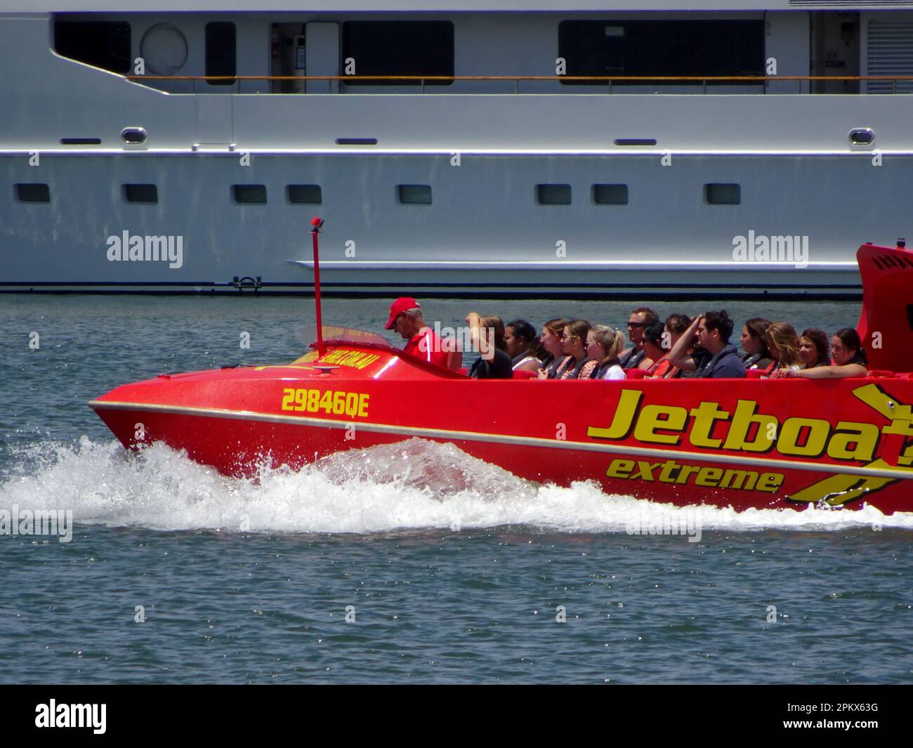 Thrill ride of Jetboat full of tourists on the Broadwater, Southport, Gold Coast, Australia. Red boat powered by 650 horse-power jet engine. Stock Photo