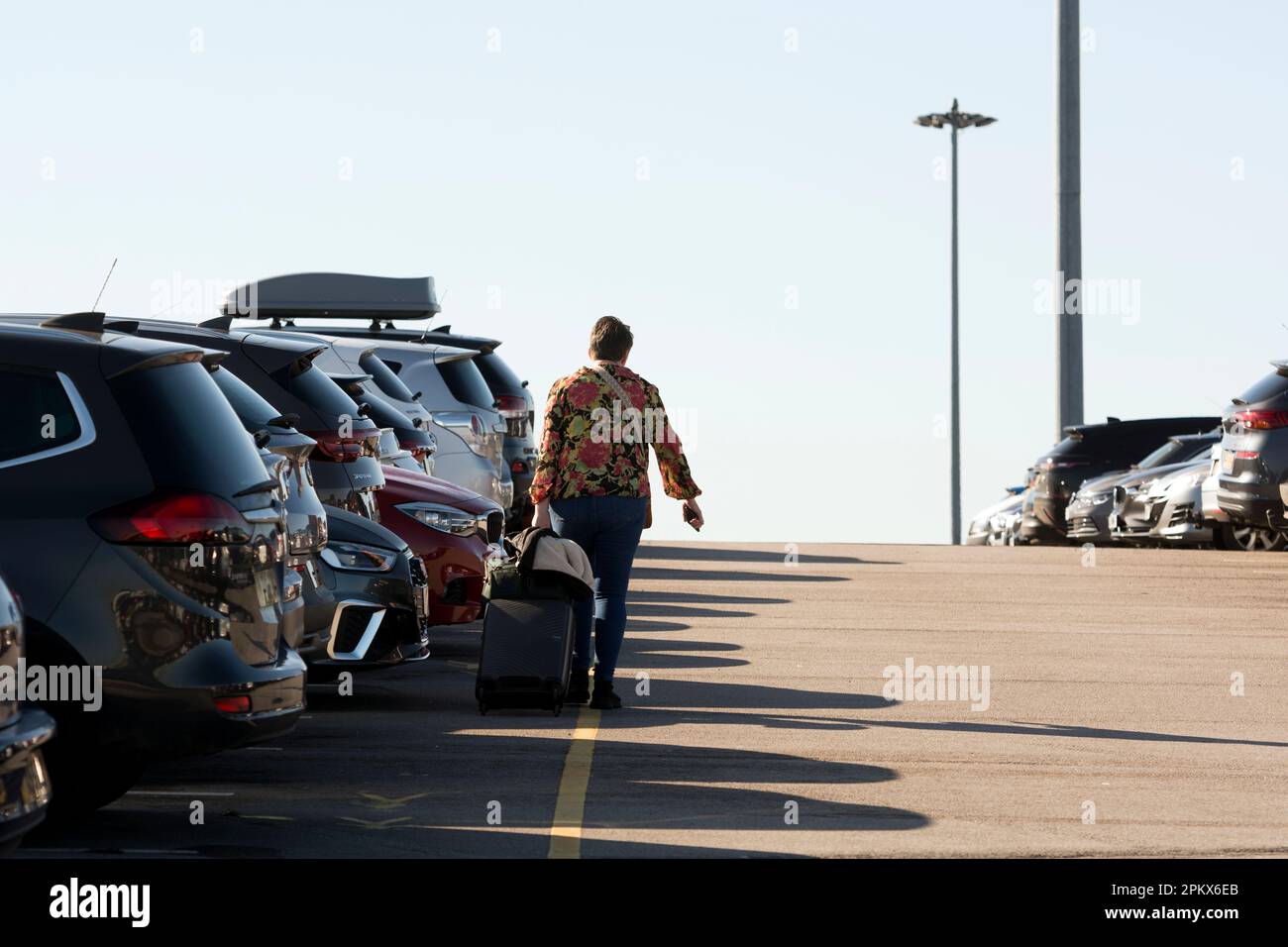 A passenger pulling luggage in the car park, Birmingham Airport, UK