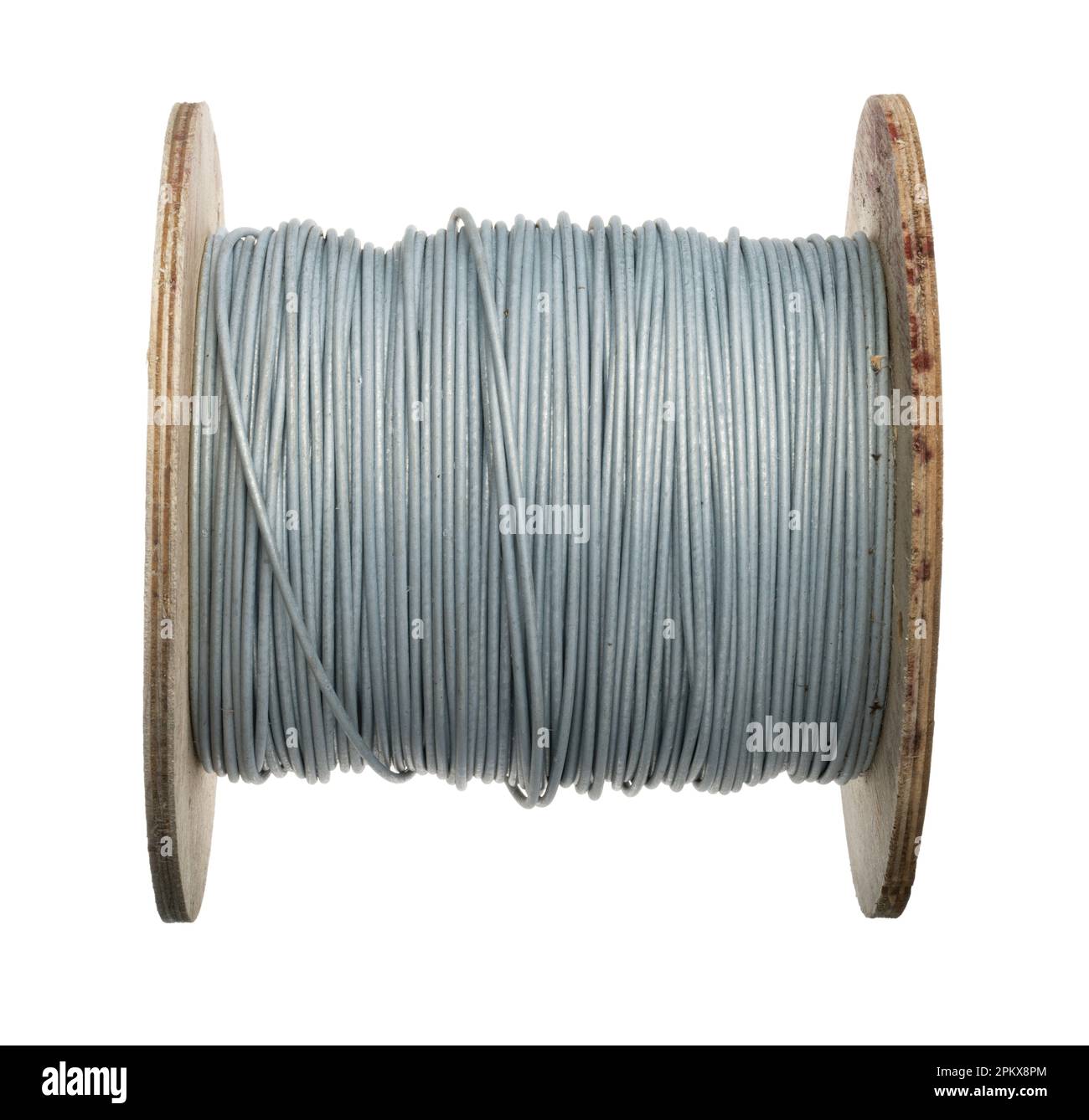A coil of fence wire. Thick gauge galvanised metal wire. Stock fencing wire on a reel or small drum. Stock Photo