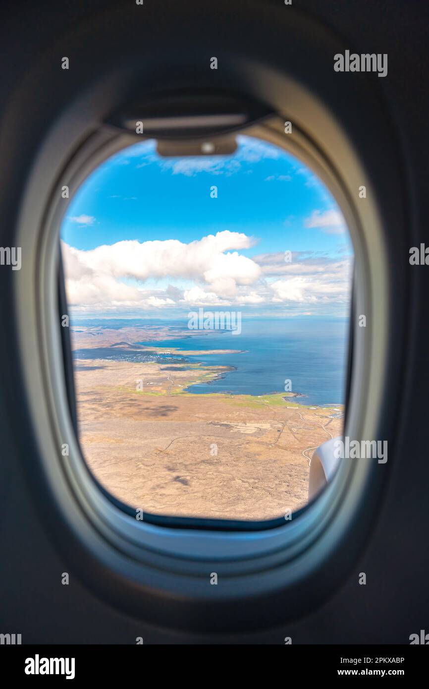 Airplane Window Frame View Flying Over Land And Ocean On Sunny Day 