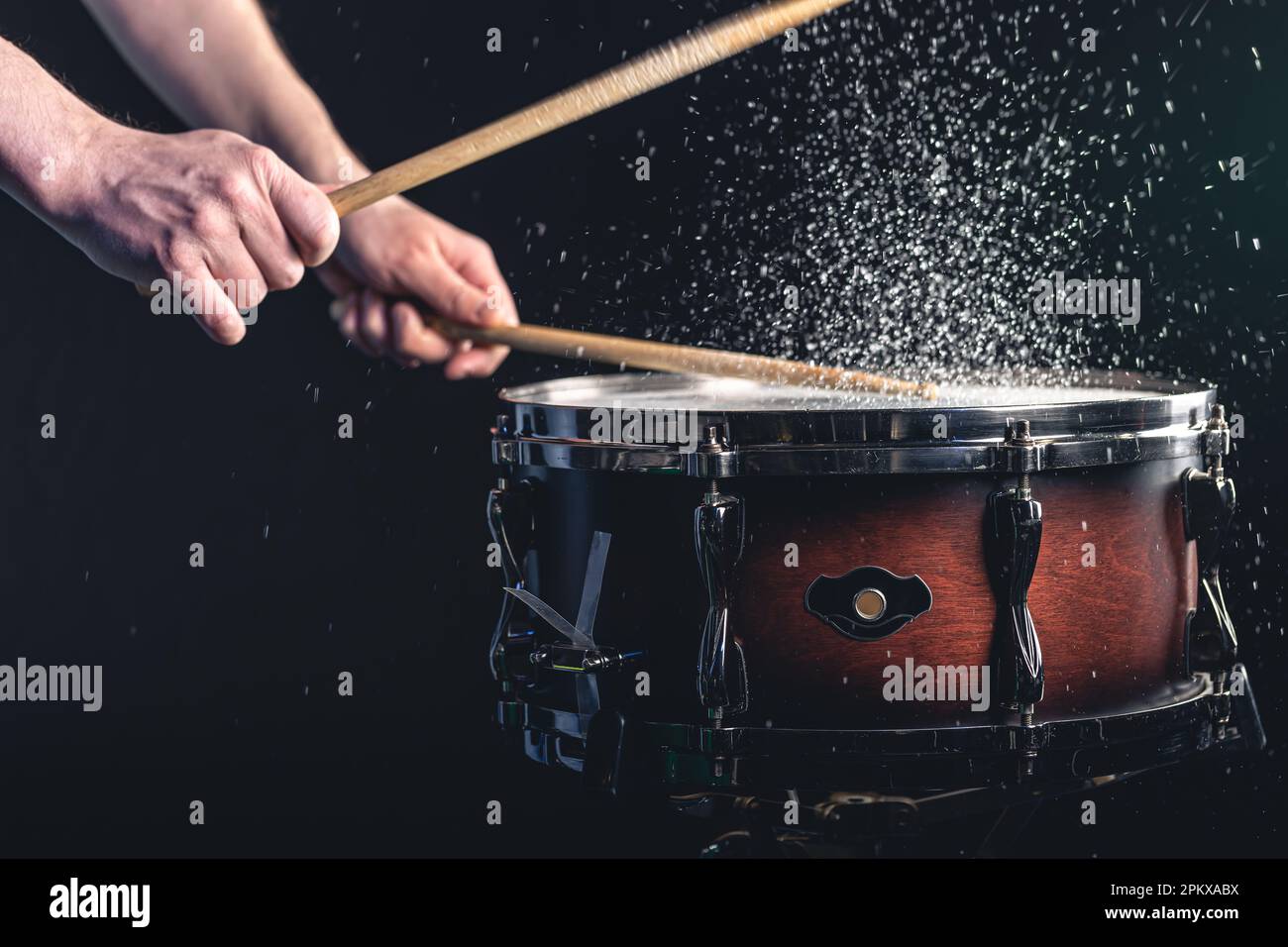Drummer using drum sticks hitting snare drum with splashing water Stock