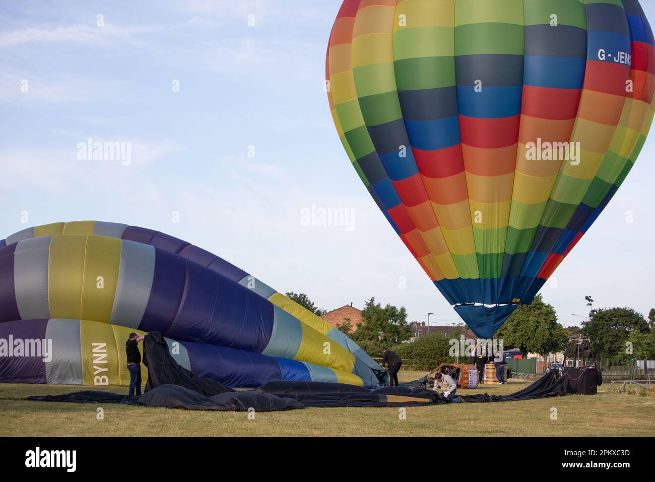People work to deflate, roll up and pack hot air balloons which have just landed Stock Photo