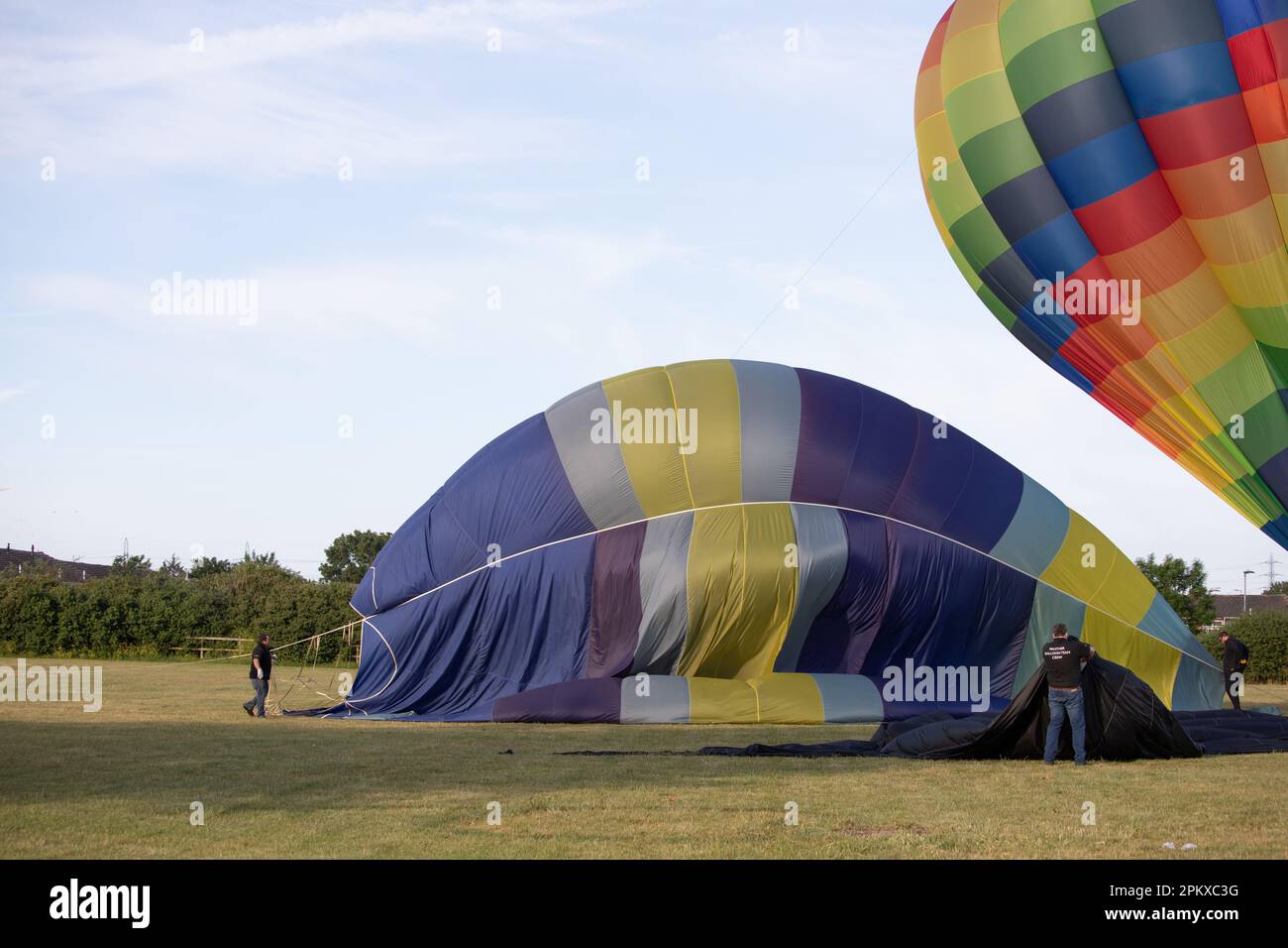 People work to deflate, roll up and pack hot air balloons which have just landed Stock Photo