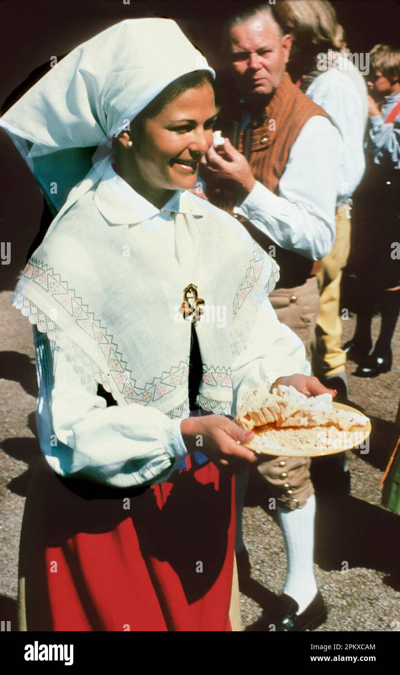 QUEEN SILVIA of Sweden in Folk costume carry a plate of food during a day at Solliden Stock Photo