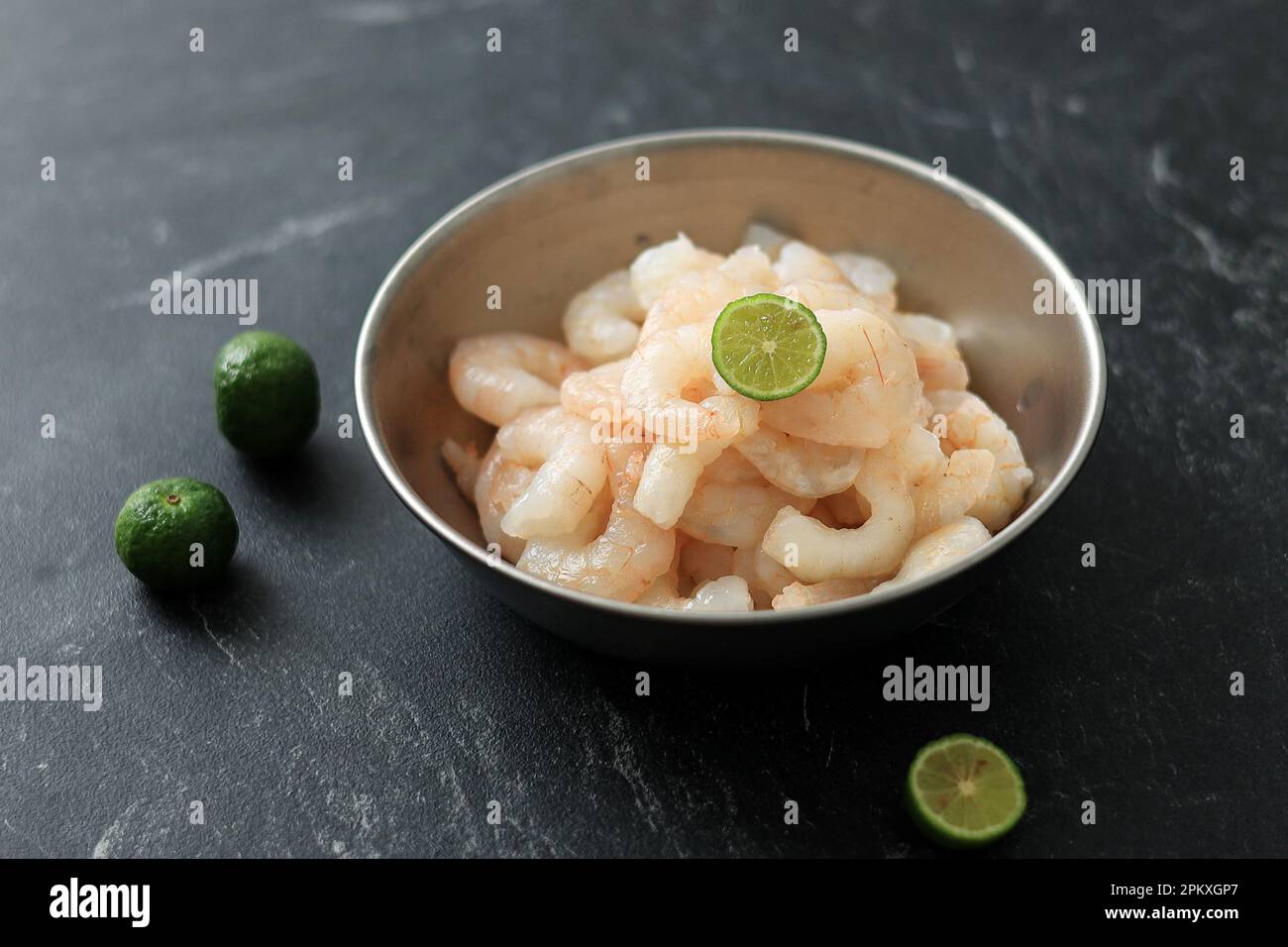 A Bowl Raw Fresh Shrimp with Lime, on Black Marble Table Stock Photo