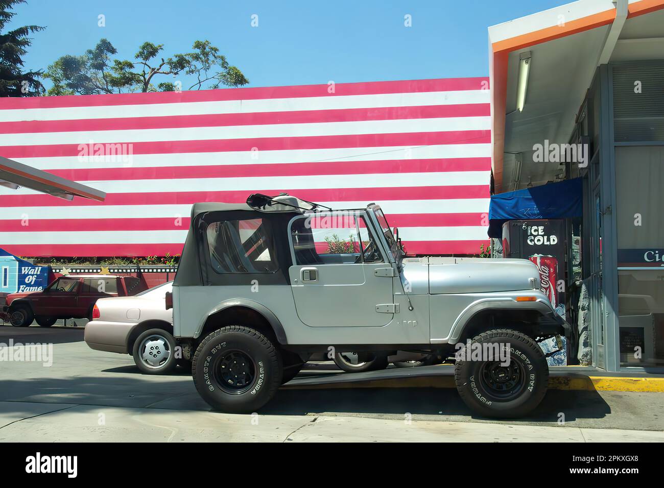 Los Angeles, California / USA, August 5, 2004: Gray Jeep Wrangler parked at a gas station in Los Angeles with a large American flag in the background. Stock Photo