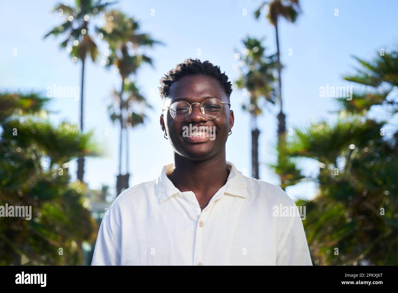 Handsome African young man looking at camera with sweet smile, standing ...