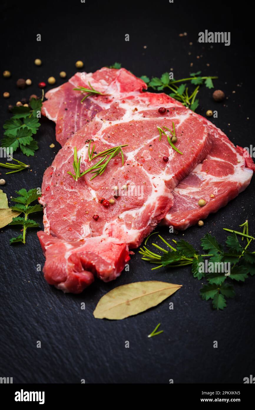 Fresh raw meat on black board with spices and herbs Stock Photo