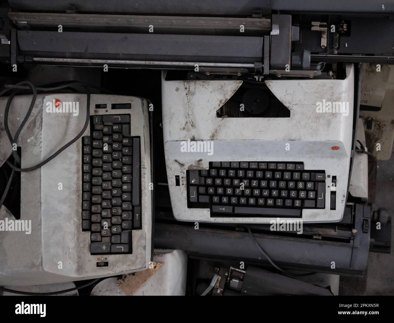 Picture of typewriters with QWERTY keywords being thrown away due to obsolescence, dirty and broken. Stock Photo