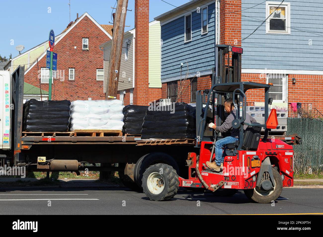 A worker operates a Hiab Moffett M4 NX forklift. The three-wheel rough terrain forklift mounts to the back of a truck and is highly manueverable Stock Photo