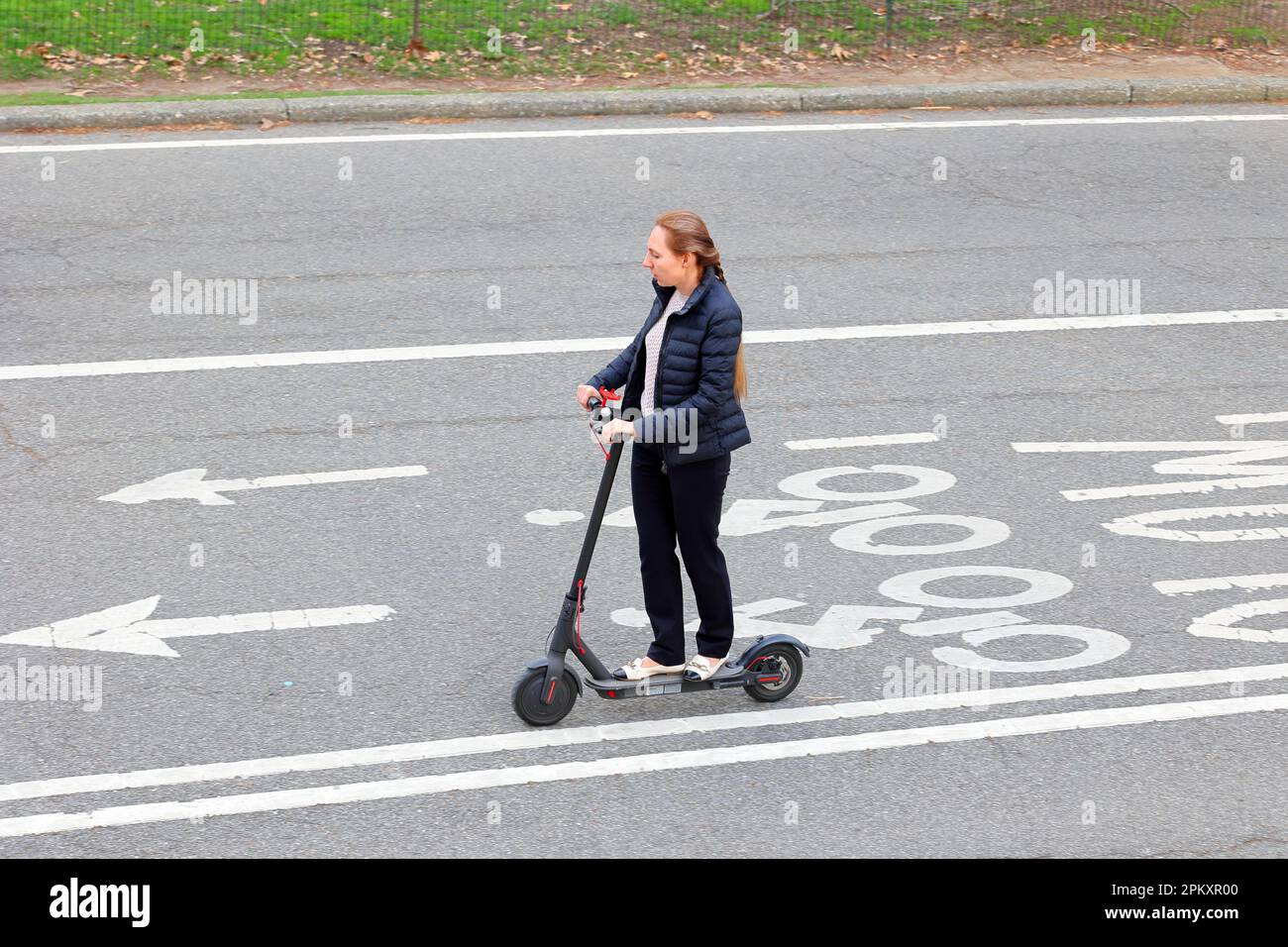 A woman commuting home from work on an electric scooter in New York City Stock Photo