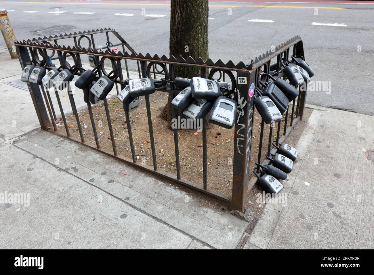 Dozens of lock boxes and key safes for pet sitter, guest self-service check-in, locked to a tree planter in Manhattan's East Village in New York. Stock Photo