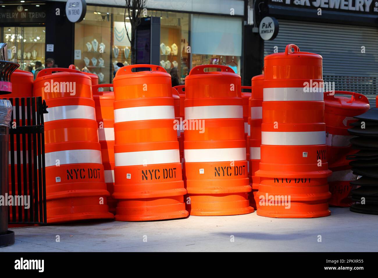 Brand new NYC DOT orange traffic drums, reflective traffic barricades, on Broadway in Manhattan in New York for construction safety flagging Stock Photo